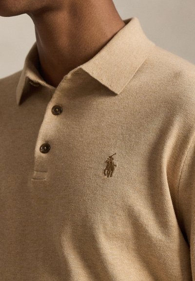 Polo beige in tessuto a maglia, con collo classico, tre bottoni e logo ricamato sul petto a sinistra. Tessitura liscia.