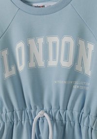 Světle modrá mikina s velkým nápisem "LONDON" tištěným bílými písmeny, s šňůrkou v pase a vroubkovaným výstřihem a manžetami.