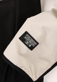 Pile nero con manica esterna liscia color crema. Presenta un'etichetta con la scritta "ACTIVE DISCOVERY RIVIVA PROJECTS" su sfondo nero.