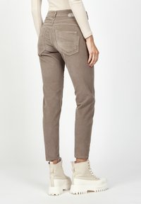 Beige corduroy pants with a slim fit, featuring back pockets and a high waist design. Worn with beige thick-soled boots.