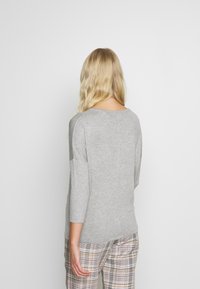 Szary długi rękaw top z okrągłym dekoltem i prążkowaną strukturą, z kontrastującymi rękawami. W połączeniu z spodniami w kratę.