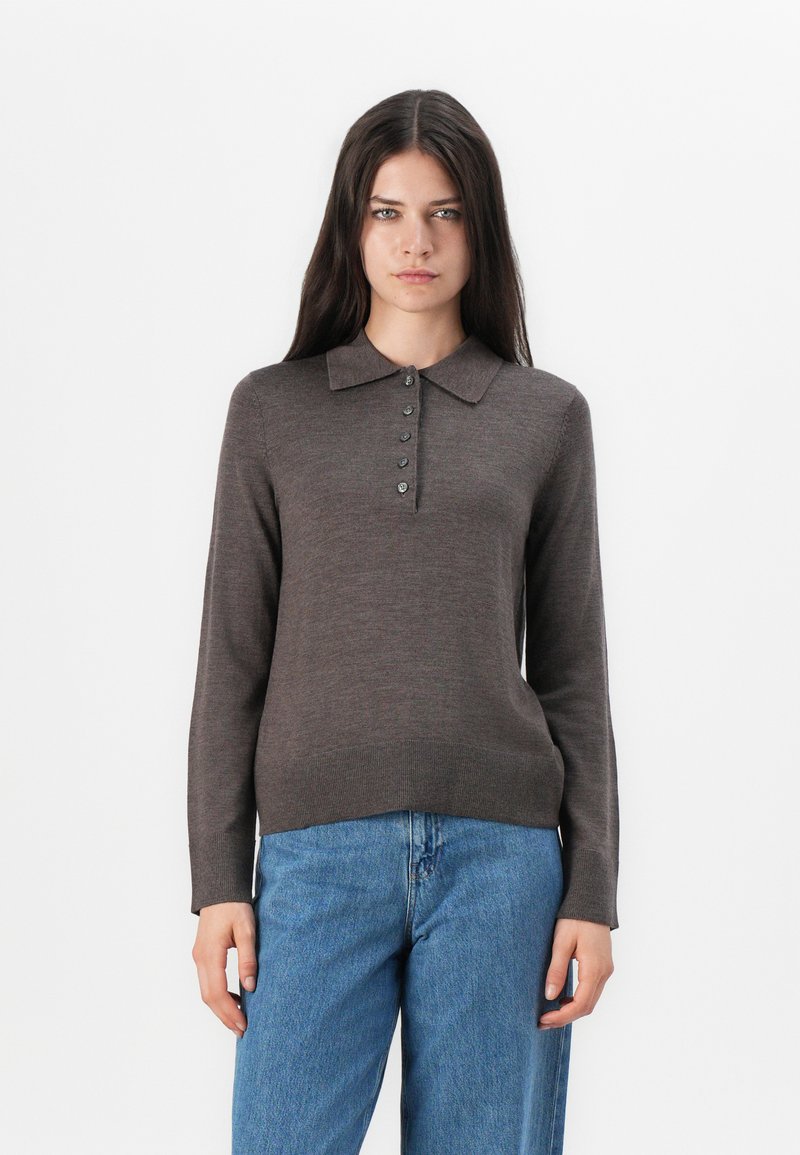 Pull en maille polo marron à manches longues avec un col côtelé, doté d'une patte de boutonnage et d'un ourlet droit, associé à un jean taille haute bleu.