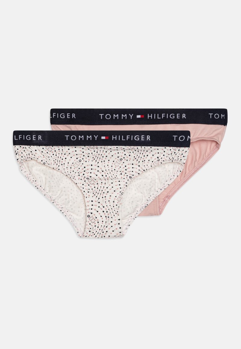 Two pairs of women's briefs: one cream with a dotted pattern, the other solid light pink; both have a black waistband with "TOMMY HILFIGER" logo.