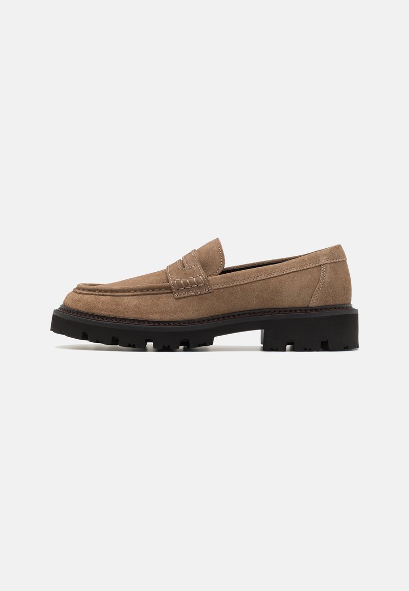 Mocassin homme en daim marron clair avec semelle en caoutchouc noir épaisse et détails cousus sur la tige et le talon.