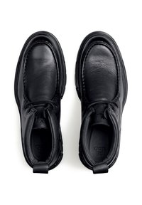 Scarpe in pelle nera con punta rotonda, lacci robusti e collo imbottito. Presentano una superficie testurizzata e una linguetta sul retro.