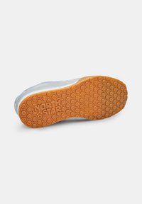 Semelle blanche de chaussure de sport avec un fond en caoutchouc orange texturé, arborant un motif en nid d'abeille et un logo "NORTH STAR" en relief.