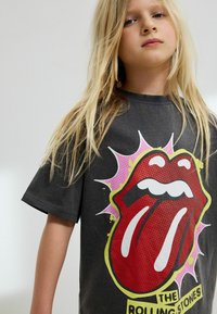 Szara bawełniana koszulka z krótkim rękawem, z dużym logo języka Rolling Stones w kolorze czerwonym, z różowymi i żółtymi akcentami oraz luźnym krojem.