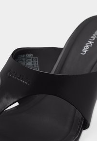 Μαύρο σανδάλι Calvin Klein με ανάγλυφο λογότυπο στο λουράκι και τυπωμένο λογότυπο στη σόλα, από λεπτό συνθετικό υλικό.