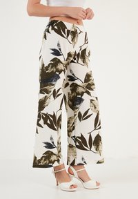 Wijde broek in lichtgewicht stof, met een witte basis en donkere groene en blauwe bladpatronen. Glad textuur en een ontspannen pasvorm.