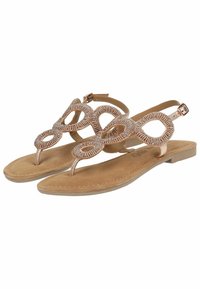 Sandali flat con una suola in suede beige, caratterizzati da cinturini metallici decorativi con ritagli circolari. Inclusa una cinghia regolabile alla caviglia.