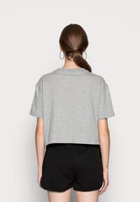 Grå bomull croppad t-shirt med korta ärmar och rund halsringning, kombinerad med svarta shorts. Tyget har en slät textur.