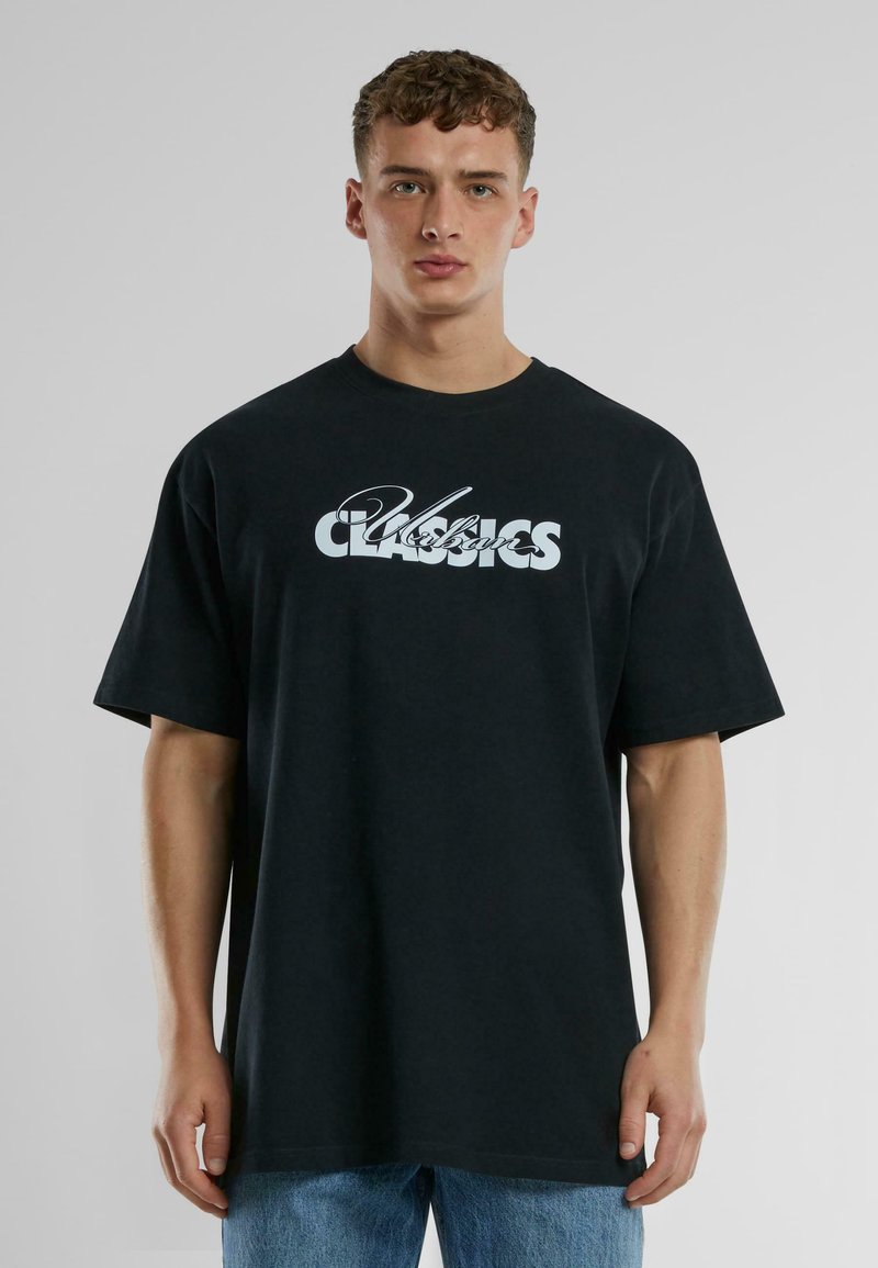 Juodas per didelis medvilnės marškinėliai su ryškiu baltu užrašu "Urban Classics" stilizuotu šriftu krūtinės srityje.