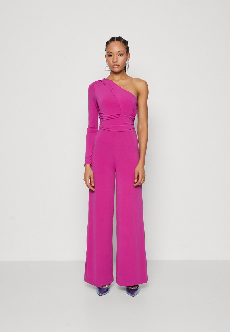Fuksia jumpsuit med én langermet, drapert design, vide ben og glatt tekstur, parret med iriserende høye hæler.