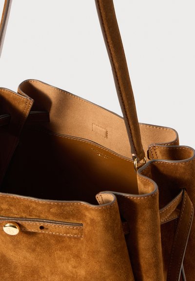 Δερμάτινη τσάντα σε θερμό καφέ χρώμα, με απαλή υφή, ανοικτό σχέδιο και εσωτερική τσέπη με λείο επένδυση. Χρυσές λεπτομέρειες.