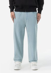 Lichtblauwe wijde spijkerbroek van denim, met contrasterende stiksels en een klein logo aan de voorkant. Gladde textuur met een comfortabele pasvorm.