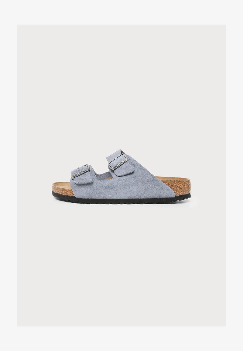 Σανδάλι Birkenstock από ανοιχτό μπλε σουέντ με δύο ρυθμιζόμενους ιμάντες με πόρπες, φελλό στο πέλμα και μαύρη καουτσούκ σόλα, εμφανίζεται από το πλάι.