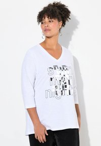 Witte V-hals t-shirt met driekwart mouwen, featuring "summer night" gedrukt in zwart en zilverkleurige folie. Zachte, lichte stof.