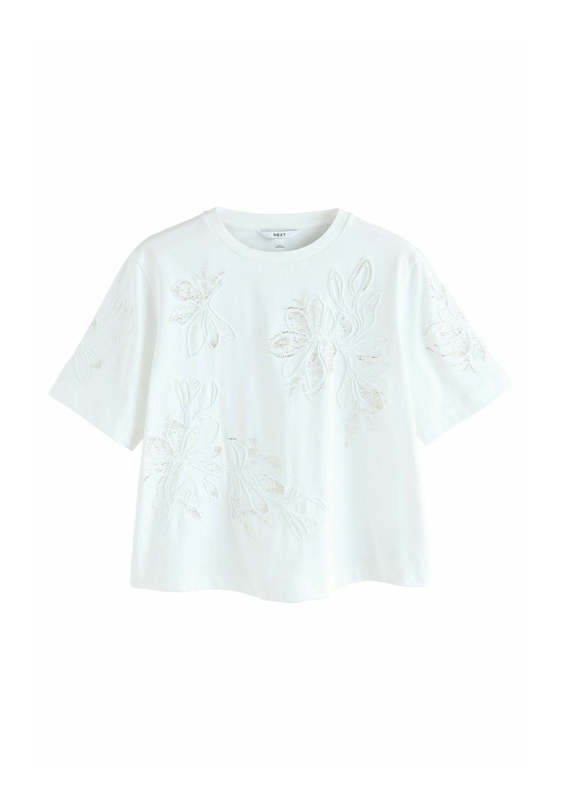 T-shirt blanc à manches courtes avec broderie florale et accents scintillants subtils. Coupe décontractée et texture douce.