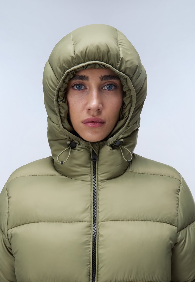Chaqueta acolchada de color verde oliva con capucha ajustada. Presenta cierre con cremallera y cordones ajustables. Tejido texturizado con secciones acolchadas.