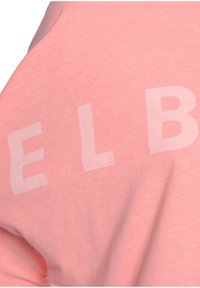 Pink short-sleeved T-shirt in soft fabric with a slightly heathered texture. Features large white block letters spelling "ELB."