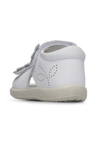 Weißer Leder-Sandalette mit flexibler Gummisohle, offenem Design und dekorativen Perforationen an der Seite. Verfügt über einen grauen Klettverschluss.