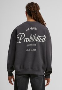 Mørkegrå sweatshirt med fed hvid tekst, der står "Forbudte Beklædningsgenstande" og dekorative accenter, med afslappet pasform og ribbede manchetter.