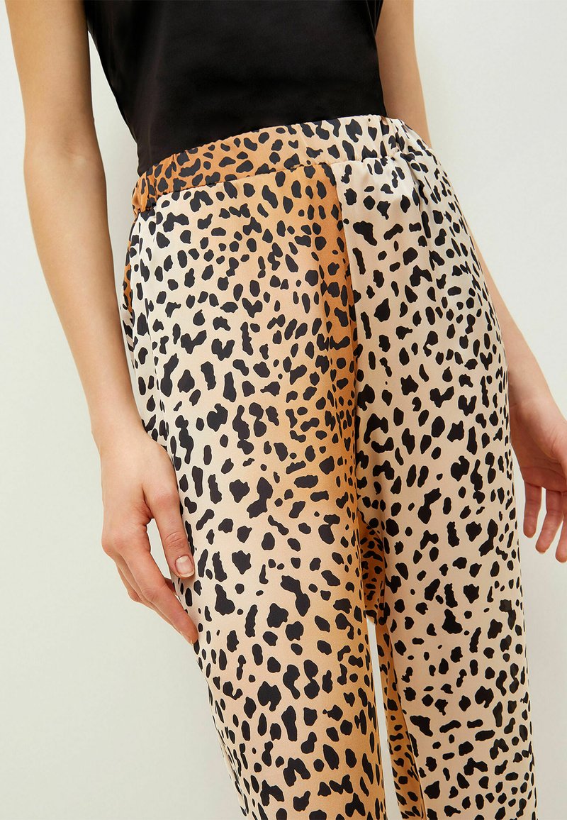 Pantalones de estampado de leopardo en tejido ligero, con manchas negras sobre un fondo beige, con una textura suave y brillante y una cintura elástica.