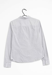 Chemise grise à manches longues avec col, arborant un subtil motif texturé et cinq boutons en accent sur les poignets.