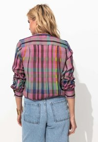 Chemise à manches longues en motif tartan multicolore présentant des nuances de rose, de vert et de bleu, avec des manches froncées et une coupe décontractée.