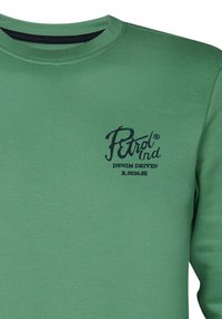 Sweatshirt en coton vert avec un col rond, présentant un petit logo noir et du texte à l'avant, mettant en avant un design et une texture décontractés.