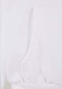 Hvit sweatshirt med en frontlomme, ribbestrikkede mansjetter og glatt tekstur. Stoffet virker mykt med et rent, minimalistisk design.