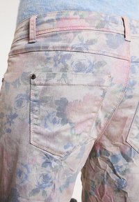 Blommönstrade jeans i pastellfärger, med en mjuk denimtextur, två bakfickor och sydda detaljer längs midjan.