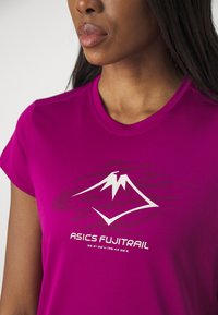 Camiseta atlética fucsia hecha de un tejido suave y ligero, con un logotipo de montaña blanco y el texto "ASICS FUJITRAIL".