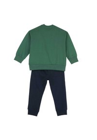 Sweatshirt vert à manches longues et poignets côtelés, associé à un pantalon bleu marine, doté d'une poche arrière et d'une taille élastique.