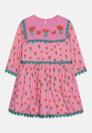 Pinkes Langarmkleid mit grüner, gewellter Kante, roten und grünen Blumen- und Herzmustern sowie einem Vorderteil mit Stickereien von Blumen und Herzen.