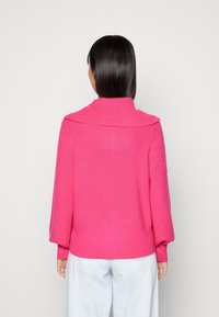 Jersey de punto fucsia con un amplio cuello de solapa, mangas largas tipo globo y dobladillo acanalado, que exhibe un material suave y texturizado.