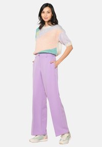 Colorful knit sweater featuring pastel hues of pink, blue, and green. High-waisted lilac trousers with wide legs and side pockets.