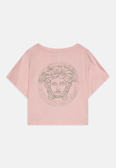 Camiseta de algodón rosa con mangas cortas, con un gráfico circular de Medusa en el centro y un patrón de clave griega alrededor del borde.