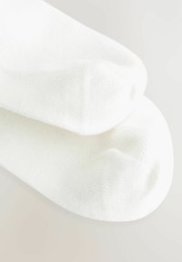 Białe bawełniane skarpetki z prążkowaną teksturą, o gładkim wykończeniu i zaokrąglonym palcem. Gruby materiał o elastycznym, miękkim odczuciu.