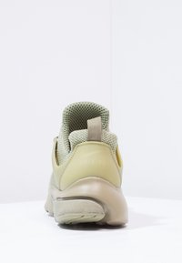 Zelená teniska s síťovaným svrškem, hladkým gumovým podpatkem a flexibilní podrážkou. Vyznačuje se prořezávaným designem a texturovaným zadním dílem.