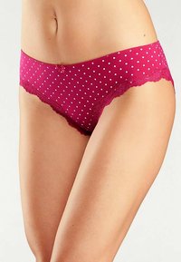 Rosa underkläder med prickar, spetskant och en liten rosett vid midjebandet, med en slät textur och kroppsnära passform.