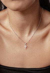 Zilveren ketting met een delicate schakel en een hangertje in de vorm van een kruis, voorzien van kleine ingelegde heldere stenen voor extra detail.