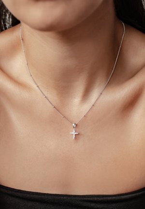 Collana d'argento con una delicata catena e un ciondolo a forma di croce, dotato di piccole pietre trasparenti incastonate per un tocco di dettaglio in più.