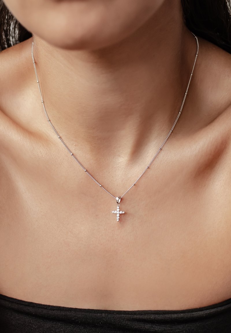 Zilveren ketting met een delicate schakel en een hangertje in de vorm van een kruis, voorzien van kleine ingelegde heldere stenen voor extra detail.