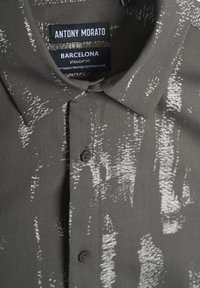 Camisa de botones gris con un estampado abstracto blanco. Confeccionada en una mezcla de algodón, cuenta con un cuello estándar y un diseño de corte recto.