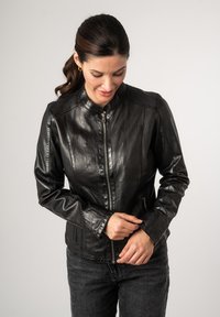 Schwarze Lederjacke mit hohem Kragen und zipbarem Verschluss. Verfügt über eine taillierte Passform und strukturierte Oberfläche. Mit Reißverschlusstaschen auf der Vorderseite.