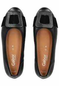 Schwarze Ballerinas mit einer quadratischen schwarzen Wildleder-Schnalle. Glattes Lederoberteil, braune Innensohle und flexible Gummisohle.