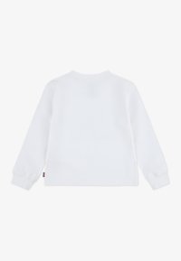 Majica dugih rukava od bijelog pamuka, s kružnim izrezom i rebrastim manžetama. Oznaka je vidljiva s lijeve strane, blizu rubnog dijela.