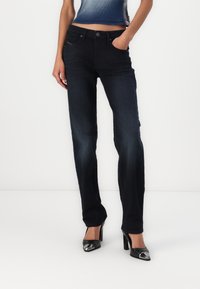 Jean en denim bleu foncé à coupe droite, avec poches avant, fermeture par bouton métal et légère décoloration du tissu.