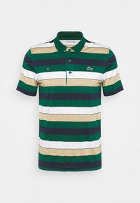 Pikétröja i gröna, marinblå, vita och beige ränder; har krage, tre knappar och en logga på bröstet. Tillverkad av bomull.